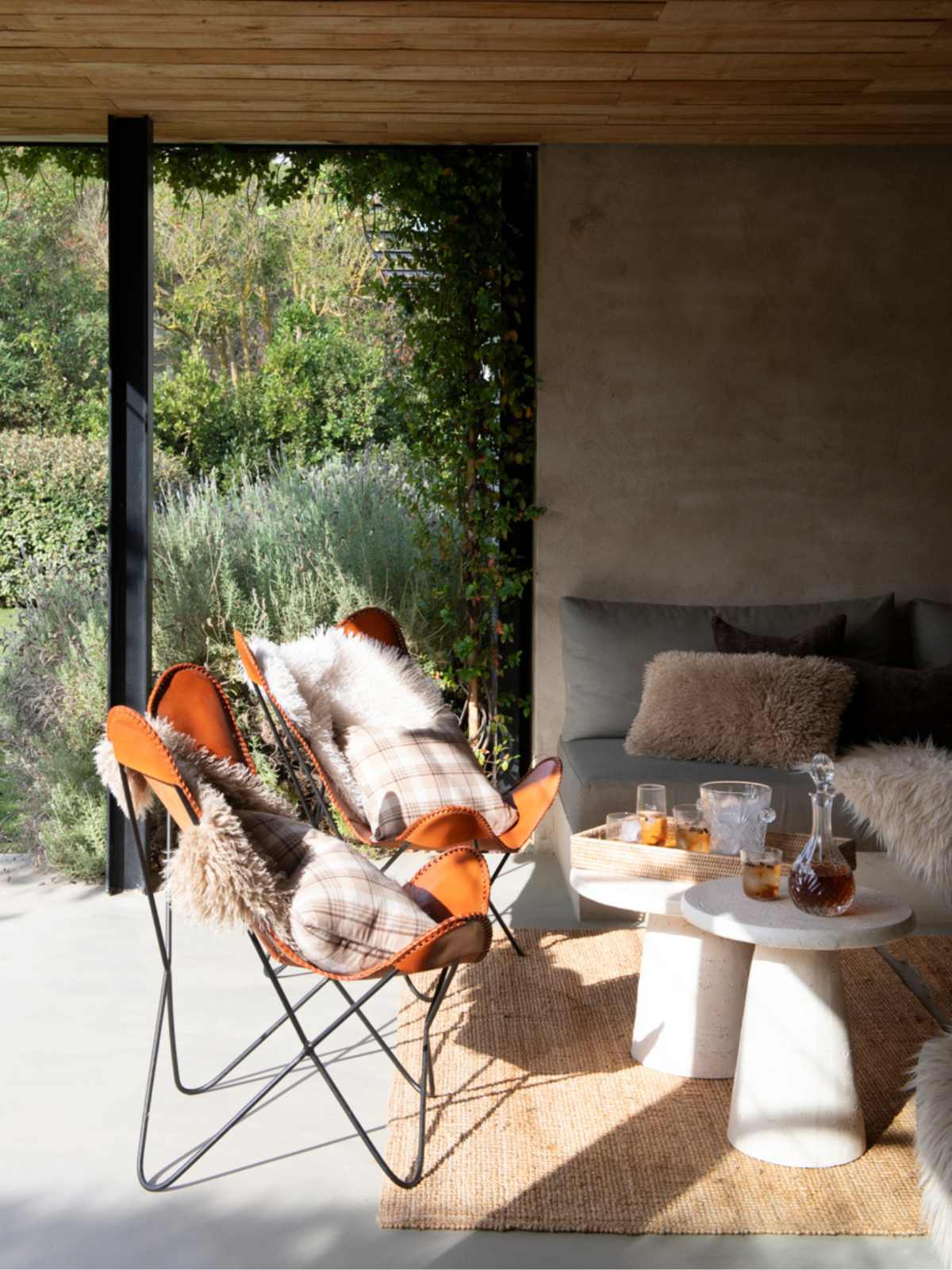 Porche exterior de invierno con sillas de cuero y cojines de cuadros y pelo.