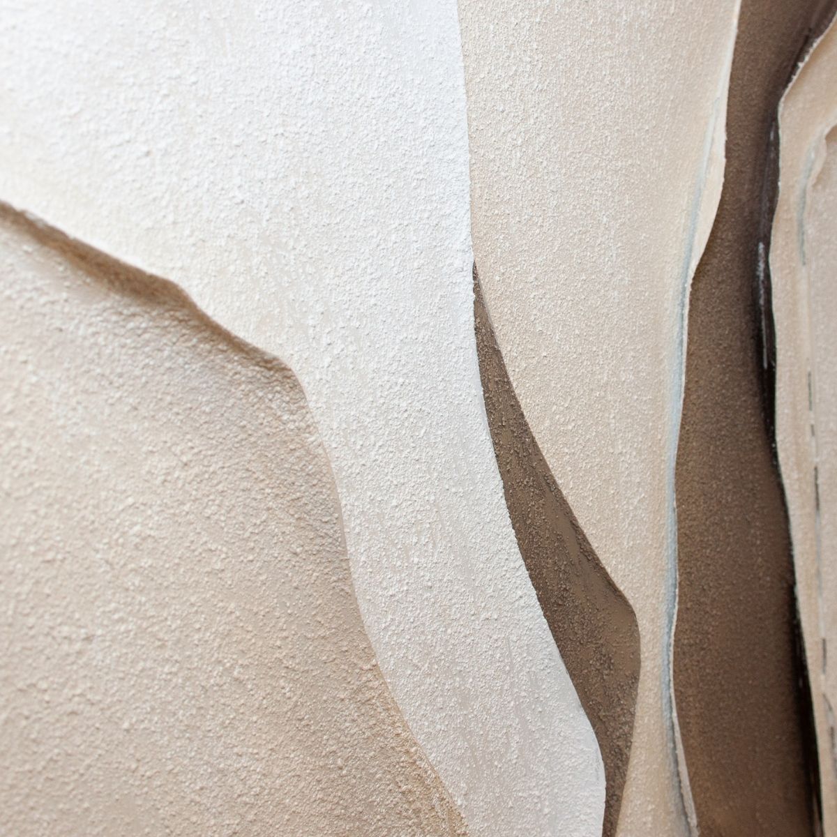 Detalle en relieve de cuadro abstracto con formas curvas y textura en tonos neutros