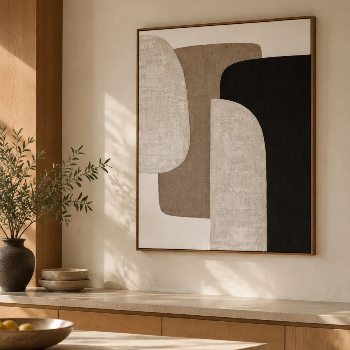 Cuadro abstracto de formas geométricas en tonos beige, blanco y negro con marco de madera, decorando un comedor de estilo mediterráneo.