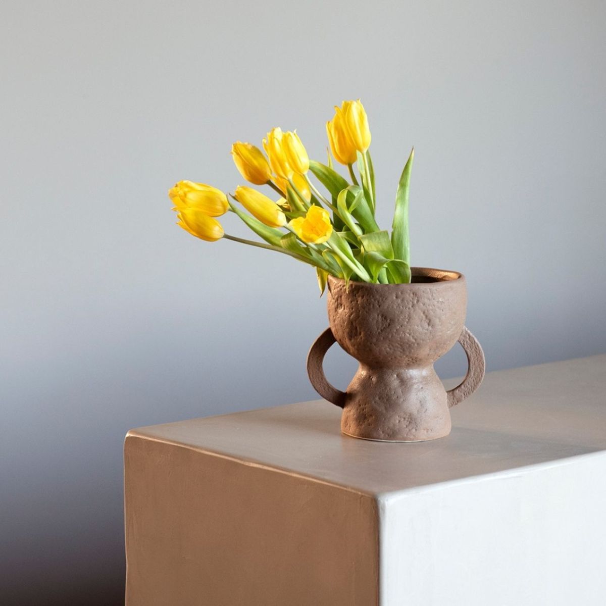 Jarrón de cerámica marrón con flores amarillas