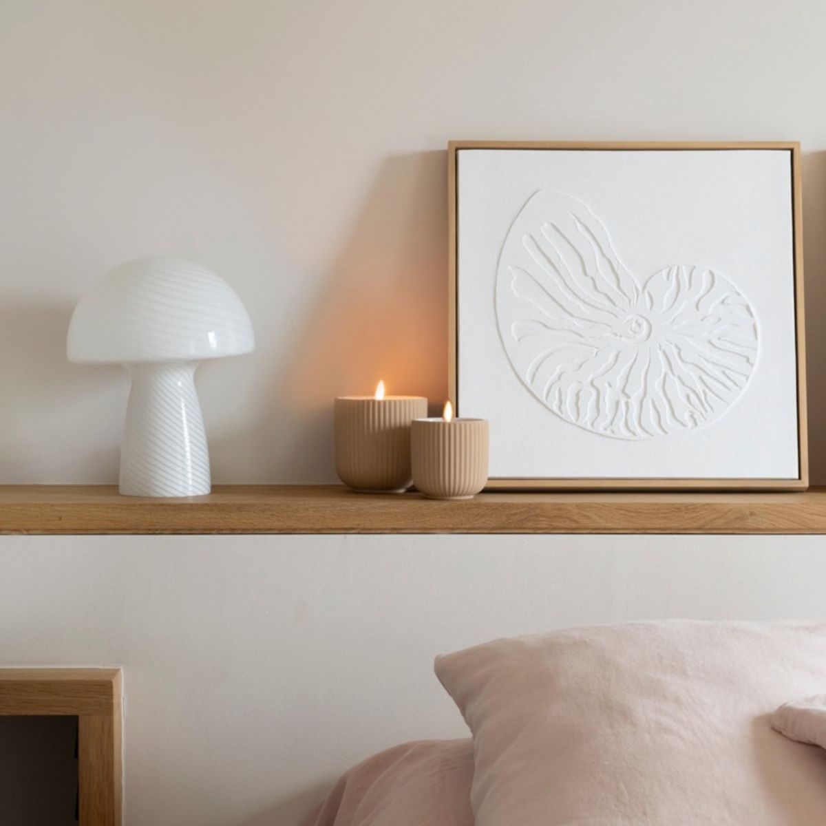 Lámpara de mesa blanca con forma de seta sobre mueble de madera en dormitorio.