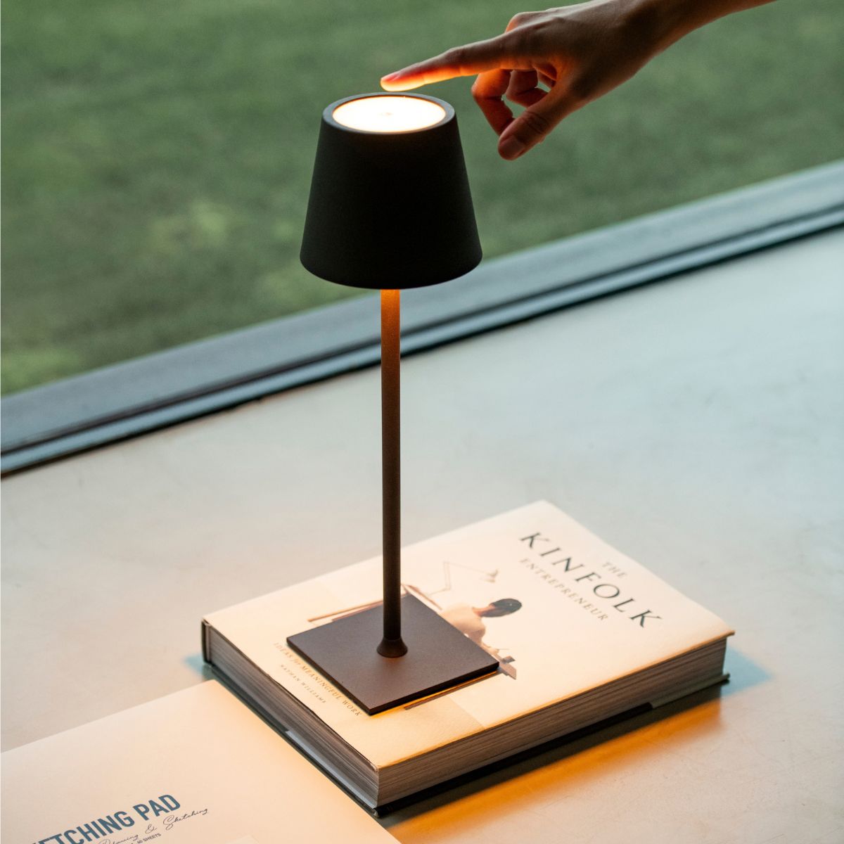 Lámpara de sobremesa negra con control táctil de encendido en ambiente interior.