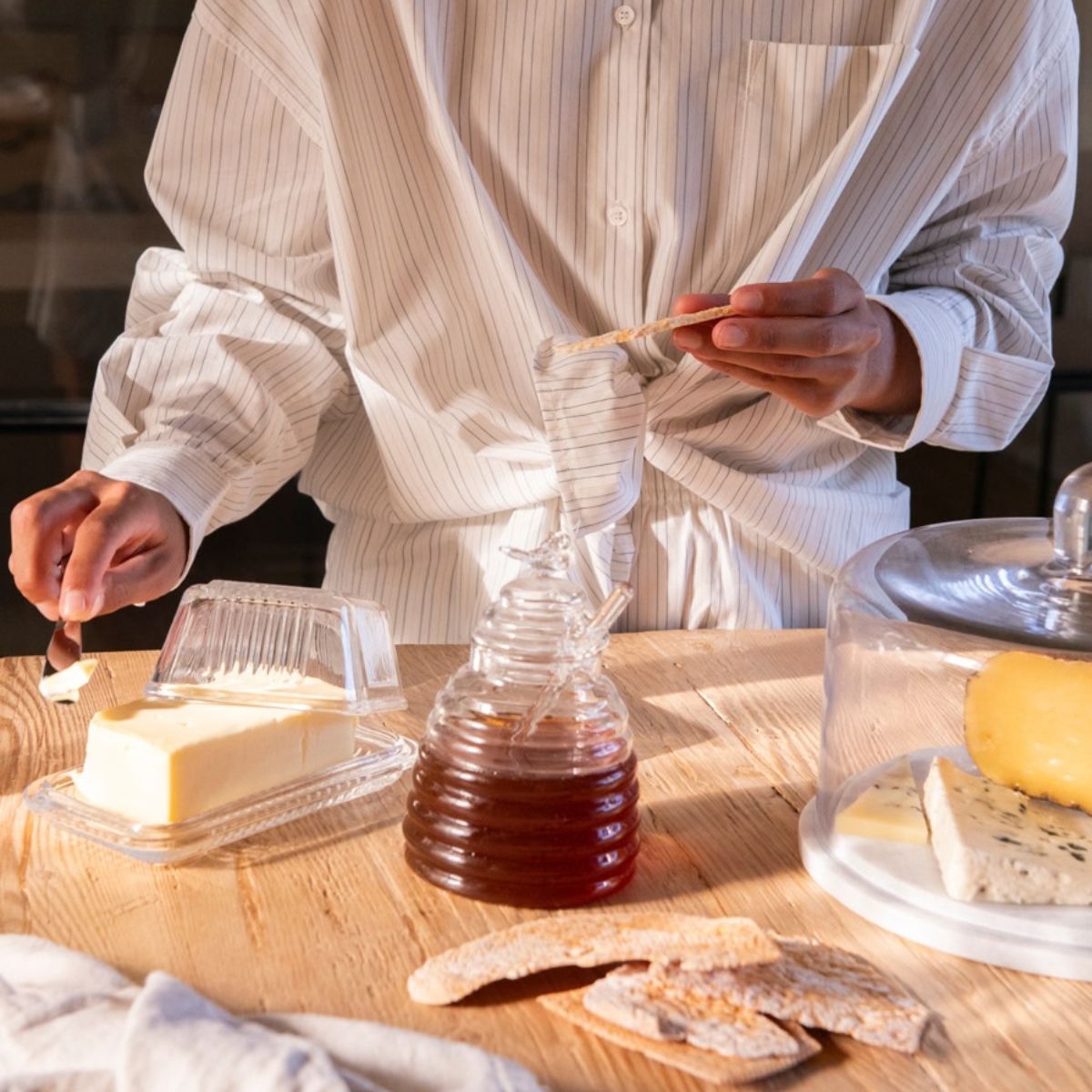 Mantequillera de vidrio con mantequilla sobre una mesa de madera durante el desayuno