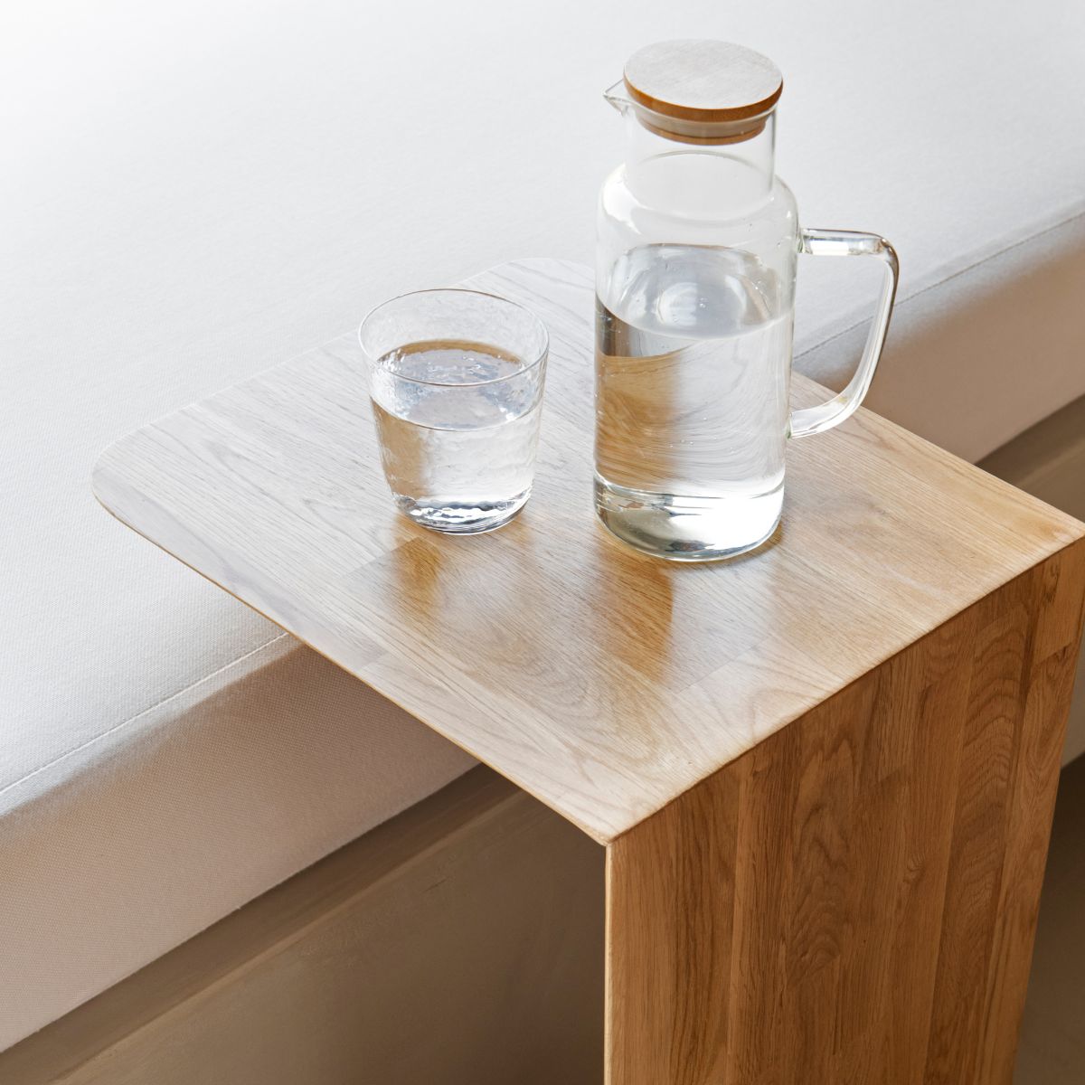 Mesa auxiliar de roble para sofá con diseño funcional en uso junto al sofá.